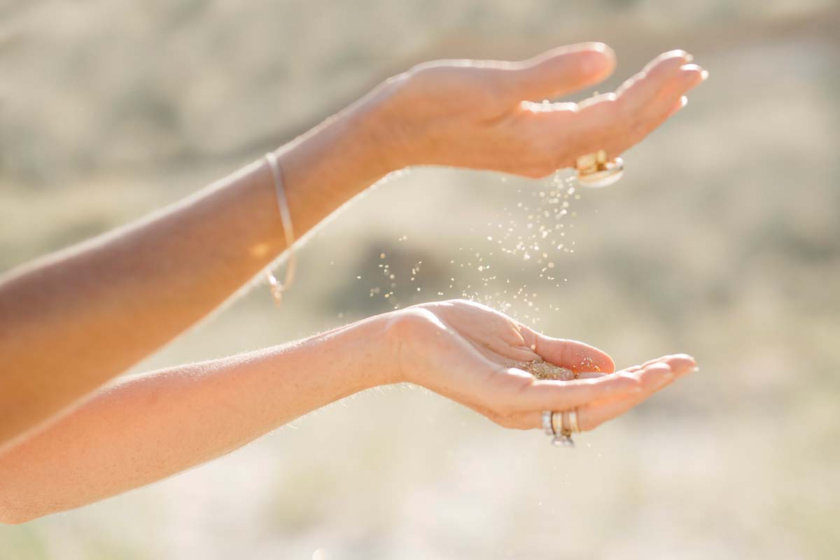 Caitlin Cady's hands holding falling sand